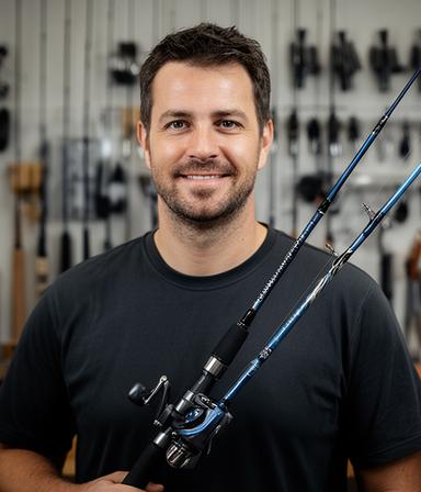 Mike, a rod builder, holding a custom fishing rod in a workshop lined with guide tools